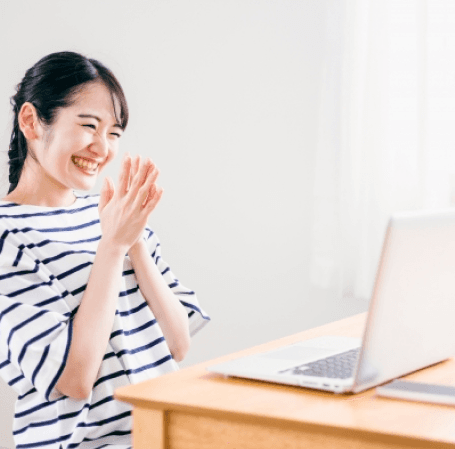 woman smiling and clapping while using laptop